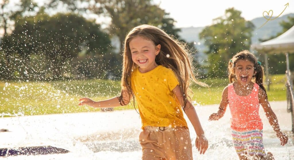 Duas meninas brincando felizes ao ar livre e com água.