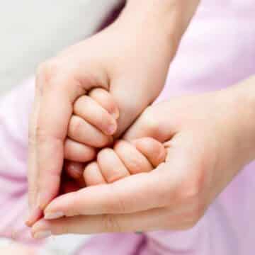 Ternura demonstrada pelas mãos de uma mãe e seu bebê em formato de coração.