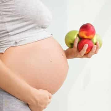 Gestante segurando frutas, dicas essenciais para saúde da gestante e do bebê