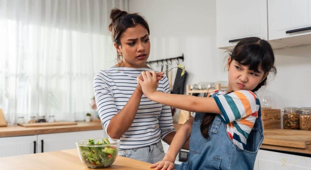 Seletividade-Alimentar-Sinais-de-Alerta Criança negando-se a comer alimentos saudáveis servidos por sua mãe.